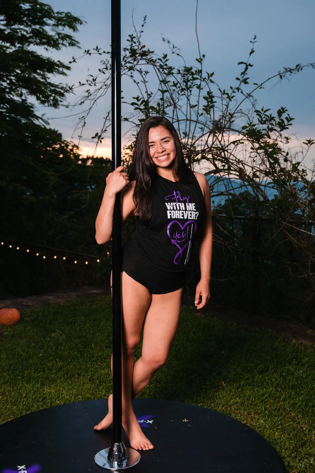 Eva Paz sonriendo junto a la barra en un jardín al atardecer
